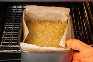 Taking the cooked flapjack recipe out of the oven holding a rubber orange oven glove